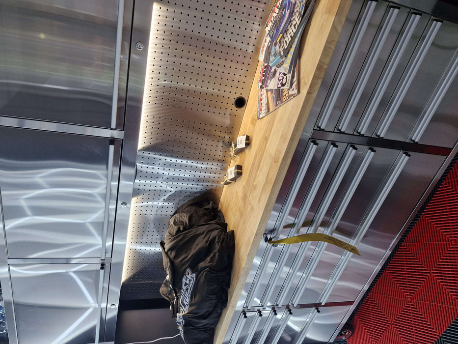 Stainless steel workshop command centre with drawers, countertop, and pegboard rear panel