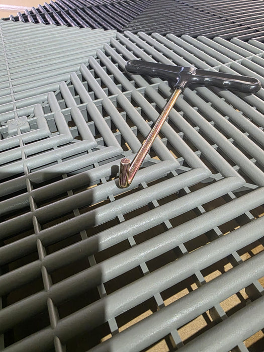 Tile removal tool with black handle inserted between ventilated floor tile openings
