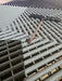 Tile removal tool with black handle inserted between ventilated floor tile openings