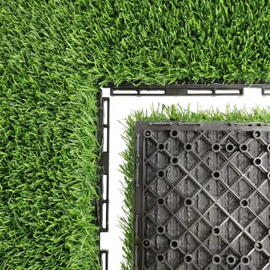 Artificial grass tile corner with dense green blades and gray grid backing