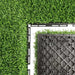 Artificial grass tile corner with dense green blades and gray grid backing