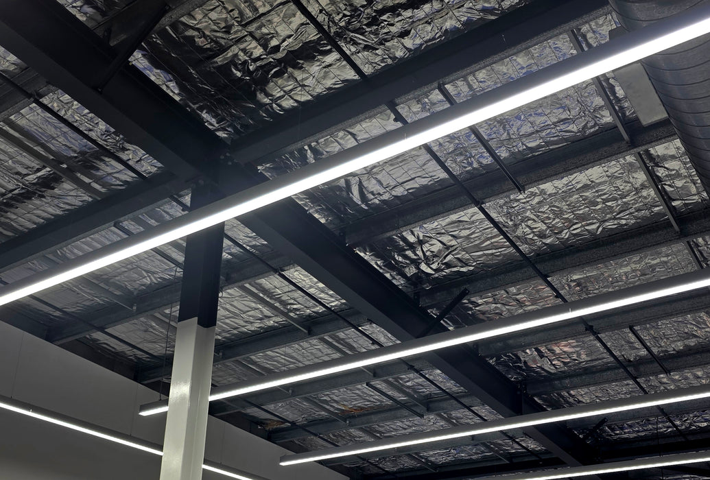 Multiple straight LED linear light bars on ceiling with bright white strips