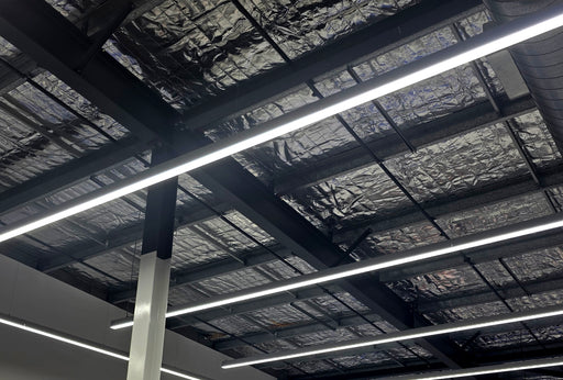 Multiple straight LED linear light bars on ceiling with bright white strips