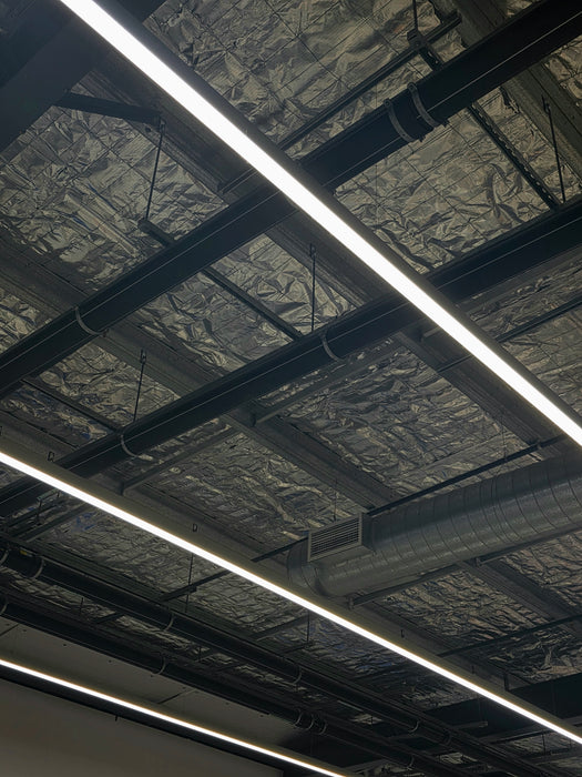 Long LED linear light bar grid on ceiling with bright white continuous lines